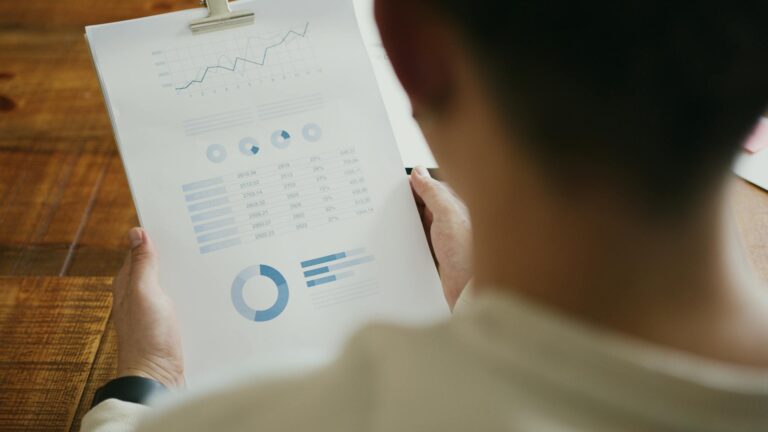 A person reviewing business performance data with charts on a clipboard in an office setting.